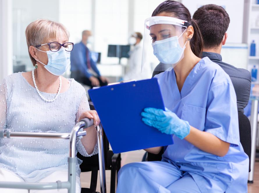 disabled-senior-woman-having-discussion-with-medical-specialist-about-treatment-hospital-hallway-wearing-face-mask-against-coronavirus-scaled