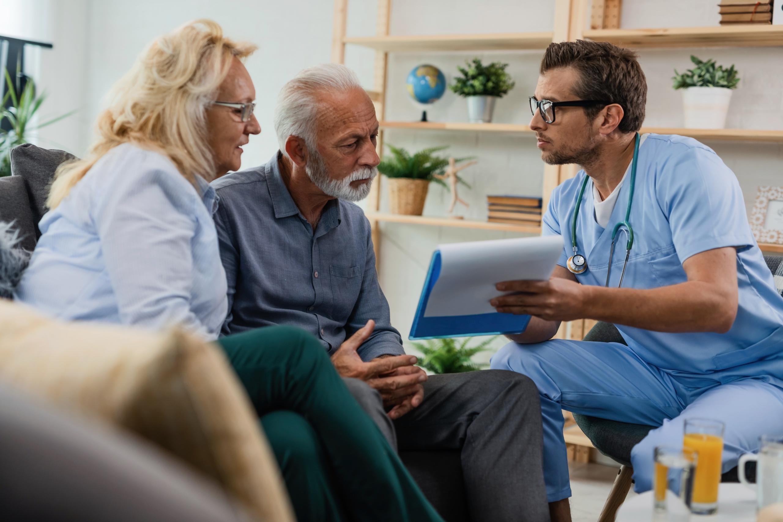 general-practitioner-showing-senior-couple-medical-documents-while-being-home-visit