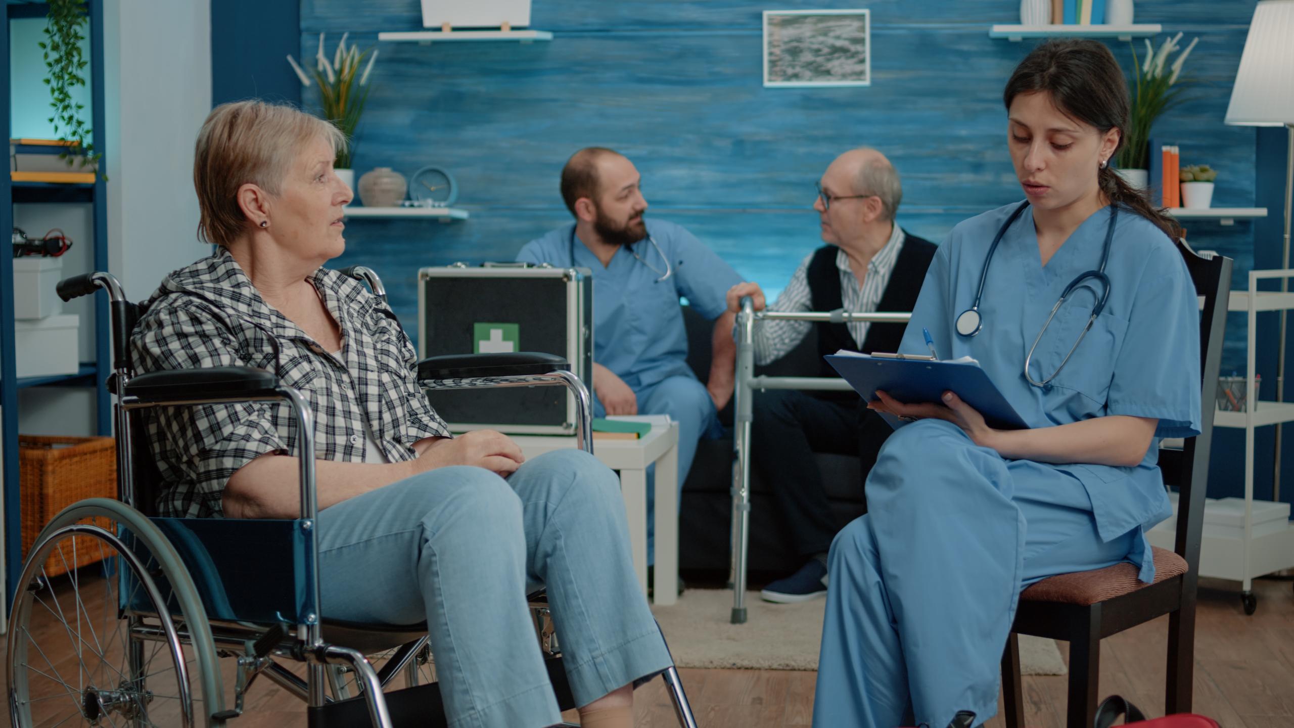 retired-woman-with-disability-talking-nurse-medical-checkup-nursing-home-healthcare-assistant-consulting-elderly-patient-sitting-wheelchair-support-assistance.