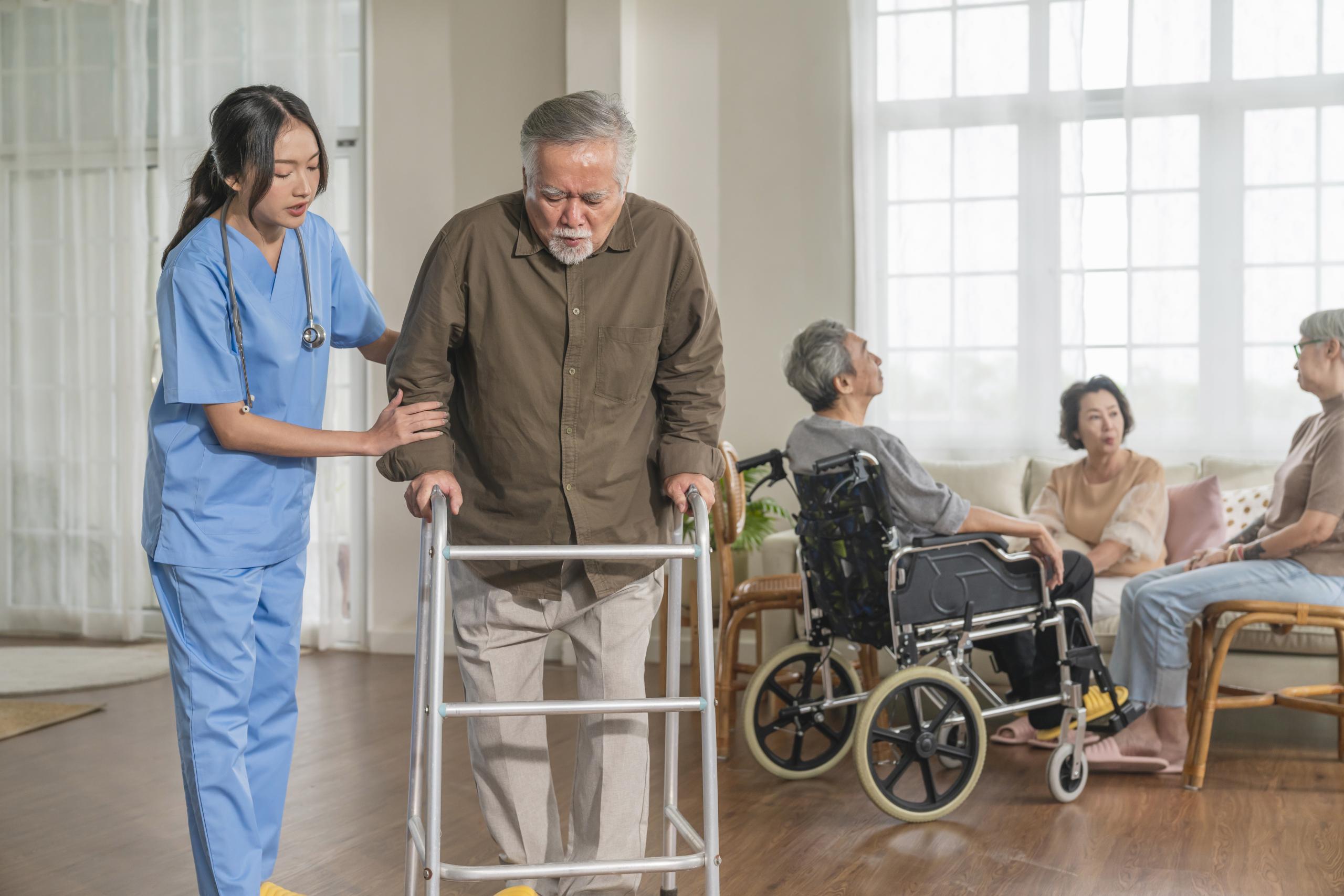 young-asian-female-nurse-care-giver-helping-asian-senior-old-man-with-mobility-walker-living-area-nursing-home-senior-daycare-centernurse-take-care-elderly-patient-with-cheerful-concentrate.
